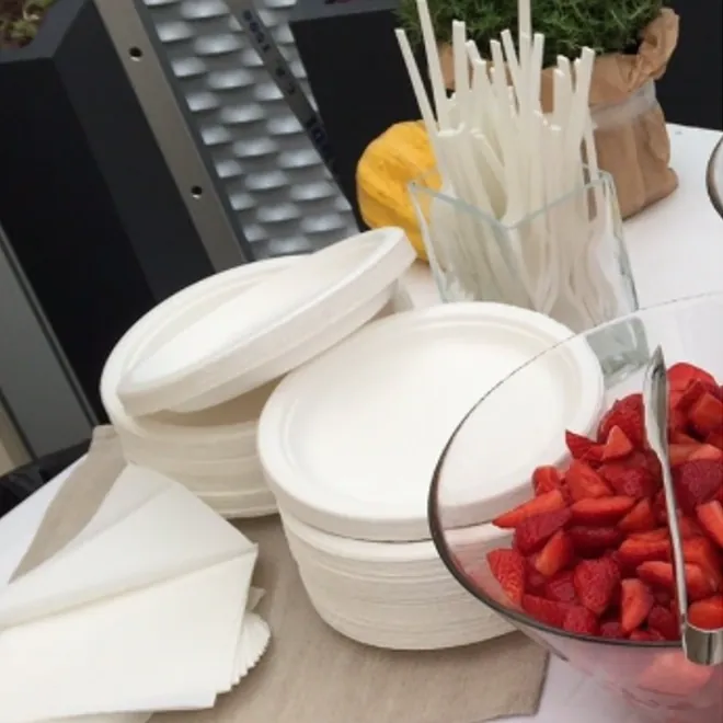 Piatti e posate in polpa di cellulosa accanto a una coppa di fragole